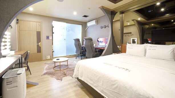 Ein Hotelzimmer mit Bett, Schreibtisch, Stühlen und Fernseher.