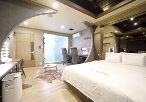 Una habitación de hotel con cama, escritorio, sillas y televisor.