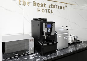 Una cafetera y una máquina de café sobre una encimera de mármol en un hotel.