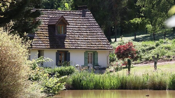 A house with a sloped roof, a small porch, and a pond in front. - La maison d’Etang (Saint-Paul-la-Roche)