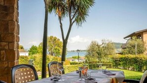 An outdoor dining area with a table set for two, overlooking a scenic view of a body of water and hills.