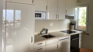 A modern kitchen with white cabinets, a built-in microwave, a double sink, and a dishwasher.