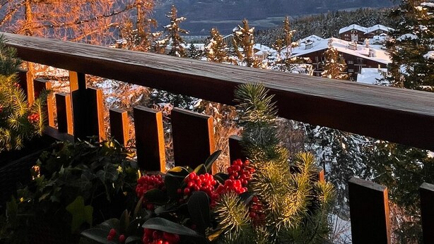 A mountain view with snow-covered peaks and a wooden balcony railing.