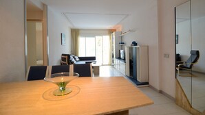 A modern hotel room with a dining table, a sofa, a TV, and a mirror. - ILLA MAR D'OR 148 (Estartit)