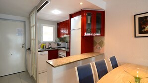 A compact kitchen with a microwave, refrigerator, and a dining area with a table and chairs. - ILLA MAR D'OR 148 (Estartit)