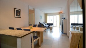 A modern living area with a dining table, sofa, and a kitchen area. - ILLA MAR D'OR 148 (Estartit)