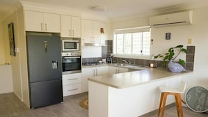 A modern kitchen with white cabinets, a black refrigerator, a microwave, a stove, and a sink.