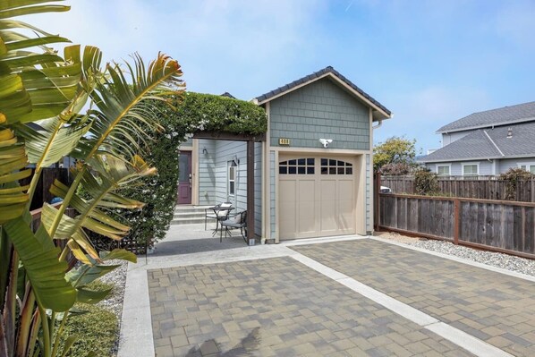 A residential property with a garage, a patio with a table and chairs, and a fenced backyard.