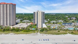 A coastal resort with high-rise buildings, a beach, and a pool area.