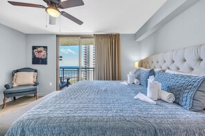 Une chambre d’hôtel avec un grand lit, un ventilateur de plafond, une chaise et une vue sur l’océan.