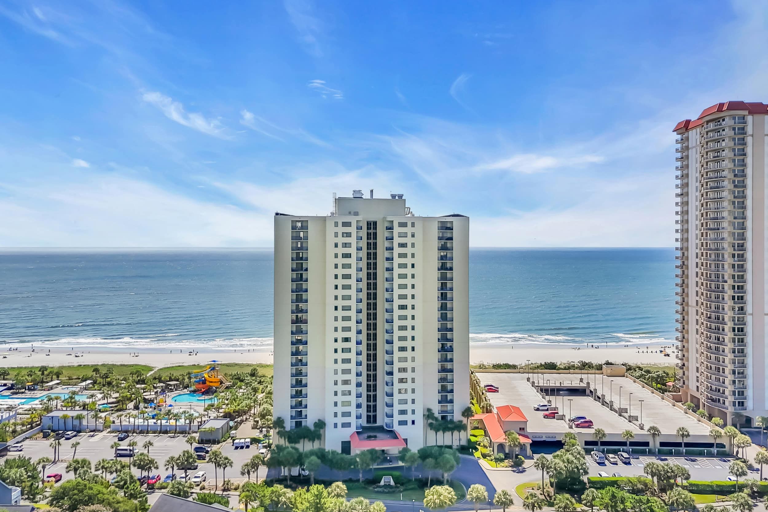 Een hoog hotel met een centrale binnenplaats, een zwembad en uitzicht op het strand.