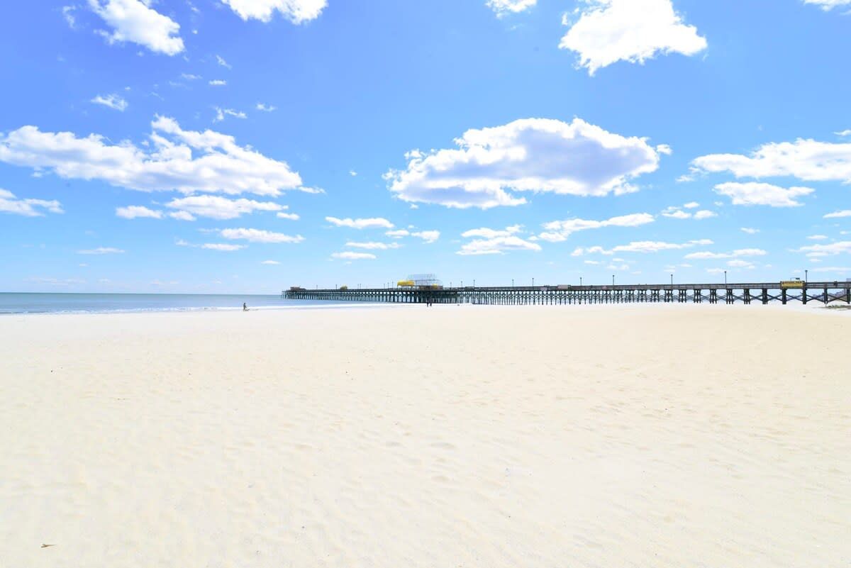 A beach with a pier extending into the water.