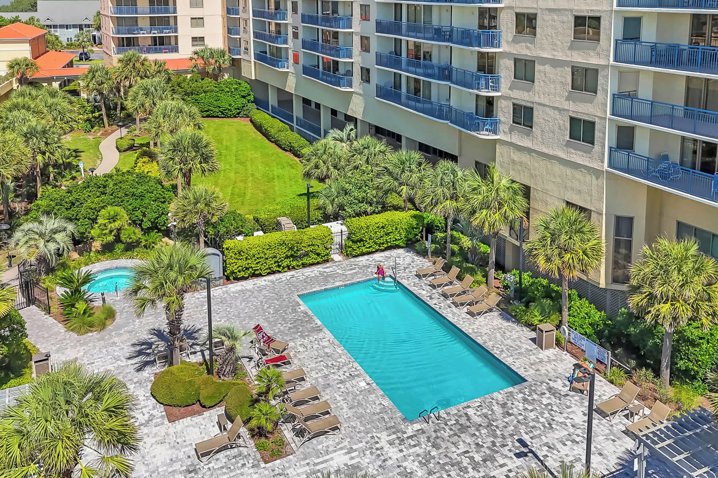 A hotel with a swimming pool surrounded by palm trees and lounge chairs.