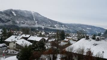 Een besneeuwd dorp met huizen en een berg op de achtergrond.