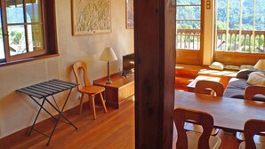 A room with wooden flooring, a dining table with chairs, a TV, a lamp, and a window with a view of trees. - 3-room apartment with balcony and parking in Samoëns (Samoëns)