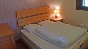 A single bed with a wooden headboard, a bedside table with a lamp, and a striped curtain. - 3-room apartment with balcony and parking in Samoëns (Samoëns)