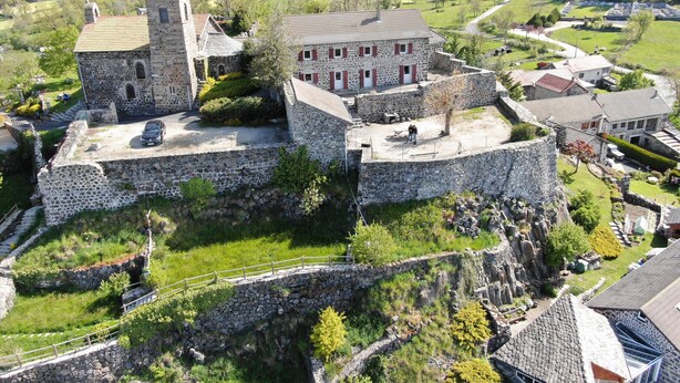 A stone castle with a central courtyard, surrounded by lush greenery and a hilly landscape. - Family cottage with yard, ping-pong, near Lyon and Clermont-Ferrand (Mézères)