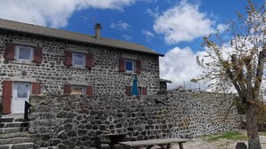 A stone building with red shutters, a wooden bench, and a clear sky. - Family cottage with yard, ping-pong, near Lyon and Clermont-Ferrand (Mézères)