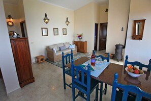 Een eethoek met een houten tafel, blauwe stoelen en een schaal fruit.