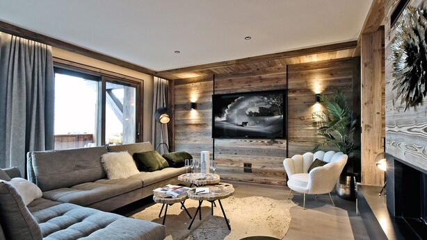 A modern living room with a sofa, armchairs, a coffee table, and a TV mounted on a wooden wall. - Méribel: 140sqm Apartment, 4 Bedrooms, Ski Access, Fireplace, WIFI, Parking (Méribel)