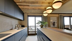 A modern kitchen with a central island, dark cabinets, and a wooden ceiling. - Méribel: 140sqm Apartment, 4 Bedrooms, Ski Access, Fireplace, WIFI, Parking (Méribel)