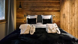 A wooden-paneled bedroom with a bed, pillows, and slippers. - Méribel: 140sqm Apartment, 4 Bedrooms, Ski Access, Fireplace, WIFI, Parking (Méribel)