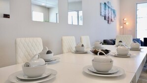 A dining area with a long table set with white tableware, including bowls and teapots, and white upholstered chairs. - Great NEW 4 bedroom townhouse in Hidden Forest, with private pool! (Clermont)