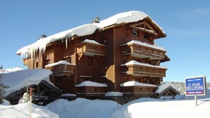 Um chalé de madeira com várias varandas, rodeado por neve.