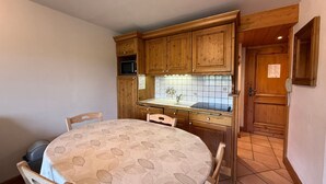 Uma cozinha compacta com armários de madeira, micro-ondas e painel de azulejos.
