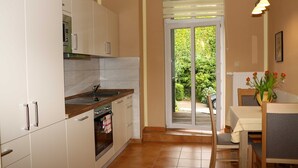 Een moderne keuken met witte kastjes, een houten aanrecht en een zithoek met een tafel en stoelen.