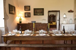 A long dining table set for a meal with candles, wine, and glassware.