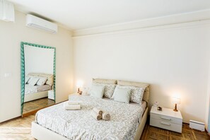 Une chambre à coucher comprenant un lit, des tables de chevet, un miroir et un appareil de climatisation.