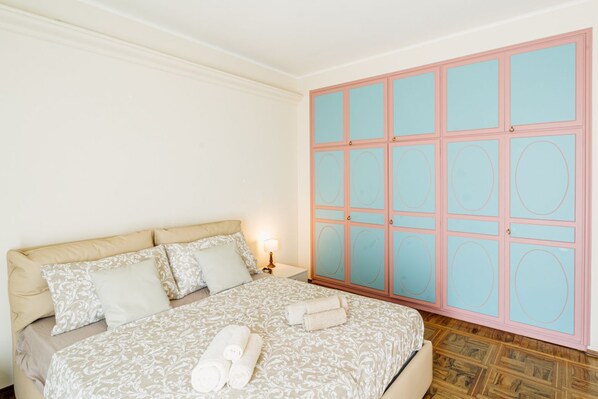 A bedroom with a bed, pillows, a nightstand, and a wardrobe.