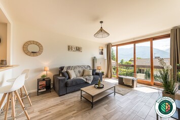 PiÚce à vivre avec canapé lit, baie vitrée avec vue sur lac et montagnes