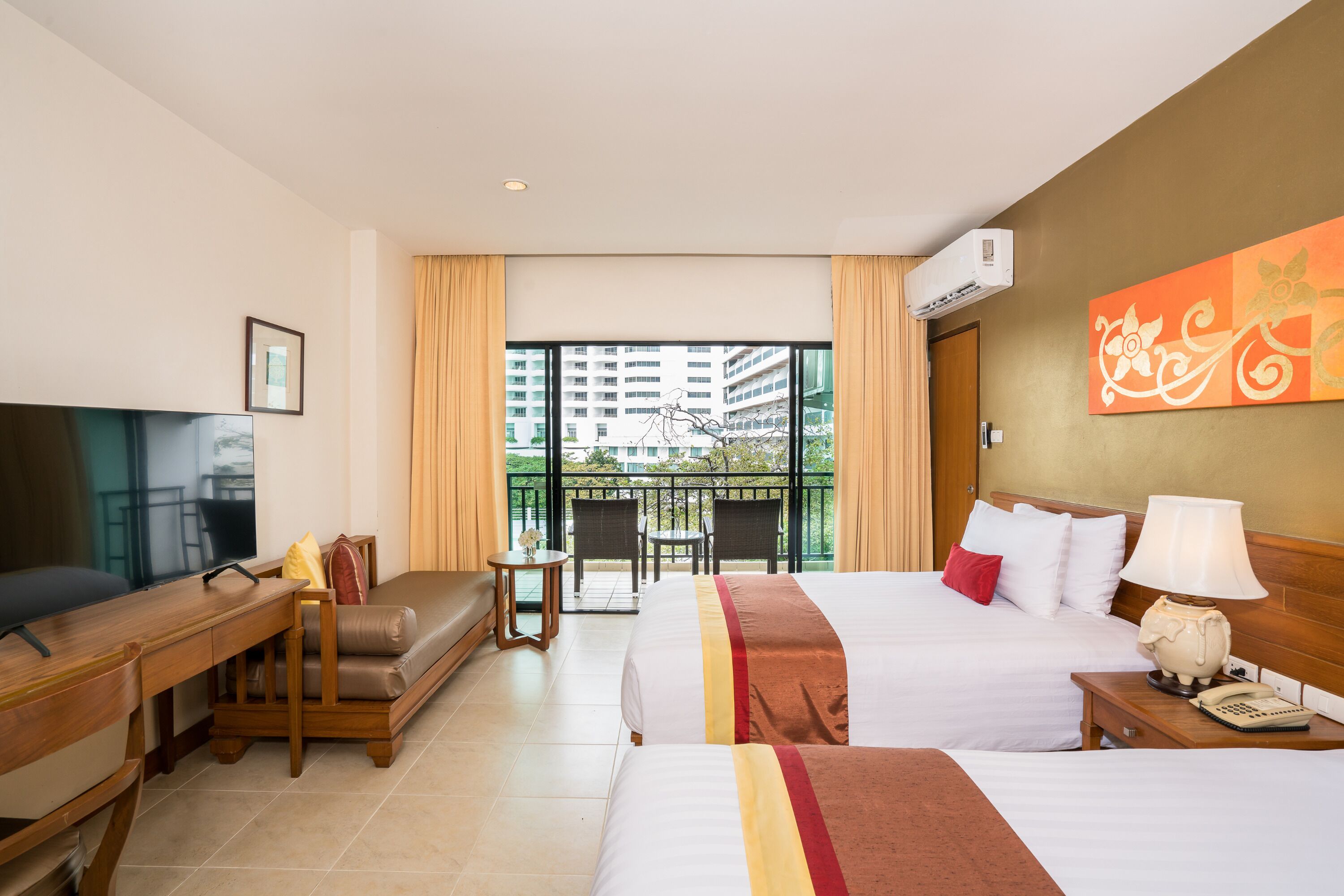 Habitación de hotel con cama, escritorio, televisor, balcón y vista a edificios, además de aire acondicionado.