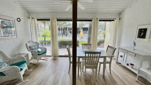 Een kamer met een eettafel en stoelen, een schommelstoel en een witte plafondventilator.