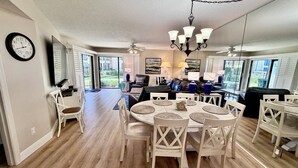Un coin repas avec une table ronde, des chaises blanches et un lustre.