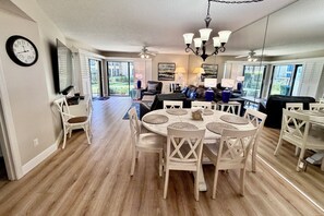 A dining area with a round table, white chairs, and a chandelier.