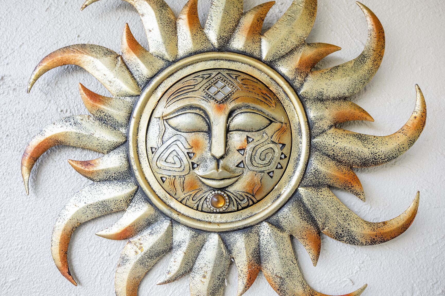 A decorative sun with a face in the center, surrounded by petal-like shapes.