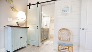 Un couloir avec une armoire bleu clair, une chaise en osier et une porte blanche.