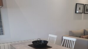 Een eetruimte met een tafel bedekt met een transparante tafelkleed, witte stoelen en een zwarte schaal op de tafel.