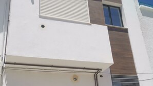 Een wit gebouw met een groot, rondboogvormig raam met een rasterpatroon, een klein raam erboven en een ventilatieopening aan de rechterkant.