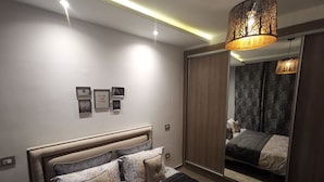 Een moderne slaapkamer met een groot bed, een spiegel en een plafondlamp.