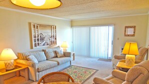 A living room with a sofa, armchairs, a wooden coffee table, and lamps. - Barefoot Country 304-Oceanfront 138th St, WIFI, Elev, W/D, AC (Ocean City)