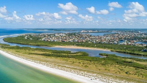An aerial view of a coastal area with a beach, a town, and a large body of water. - Beachfront 2BR condo with pool, WiFi, and heated outdoor pool. (Marco Island)