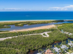 An aerial view of a coastal area with a beach, mangrove forest, and residential buildings. - Beachfront 2BR condo with pool, WiFi, and heated outdoor pool. (Marco Island)