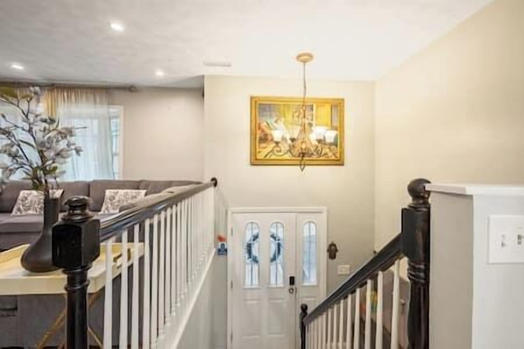 A staircase leading to a door with a glass panel, a chandelier, and a painting on the wall.