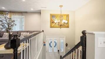 A staircase leading to a door with a glass panel, a chandelier, and a painting on the wall.