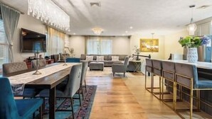 Un vaste espace de vie comprenant un grand canapé, une table à manger avec des chaises et un coin bar.