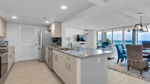 A modern kitchen with a central island, built-in appliances, and a dining area with a view of the ocean.